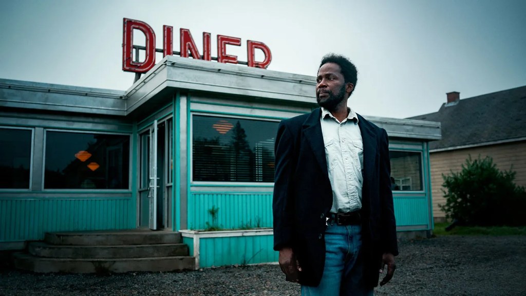 A shot of Boyd Stevens (Harold Perrineau) is an older Black man wearing jeans, a white button down shirt and a black jacket, is standing in front of a 1950's era diner.