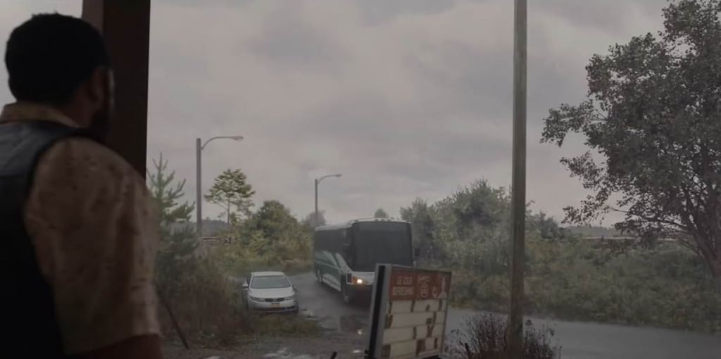 A person stands on a porch watching a charter bus drive down a loan road through a small town on a foggy day.